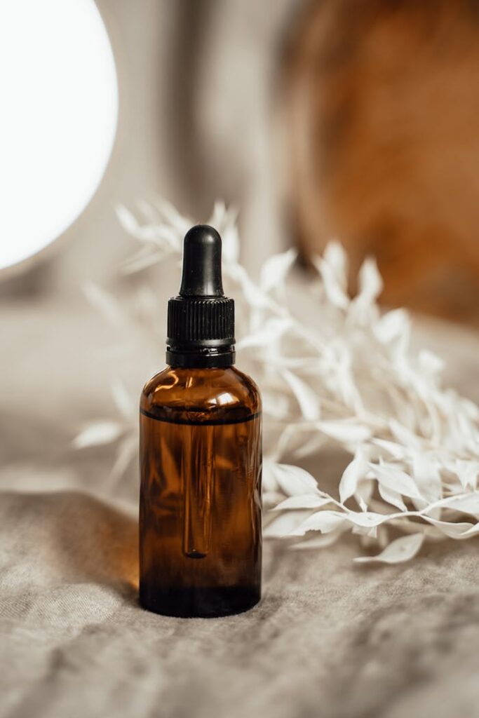 Elegant amber glass dropper bottle with organic oil and white botanicals on a cozy linen background.